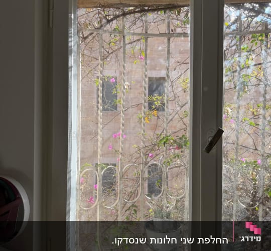 חלון עם סורגי מתכת וצמחים בחוץ